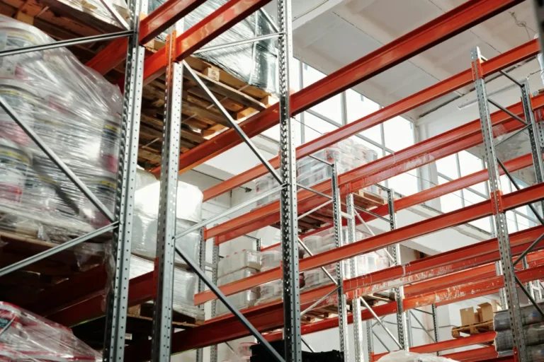 Industrial-grade storage racks with palettized goods and materials in a modern fulfillment warehouse.