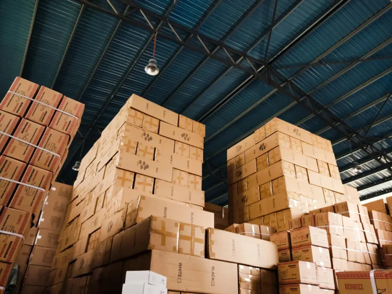 High stacks of brown shipping boxes in a large e-commerce logistics warehouse, ready for distribution.